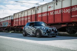 grauer John Cooper Works Mini mit einer Autohaus Firmenbeschriftung, Logo design und ausgeplottete Auflkleber auf der Heckscheibe. Eine moderne Autofolierung, Folierung