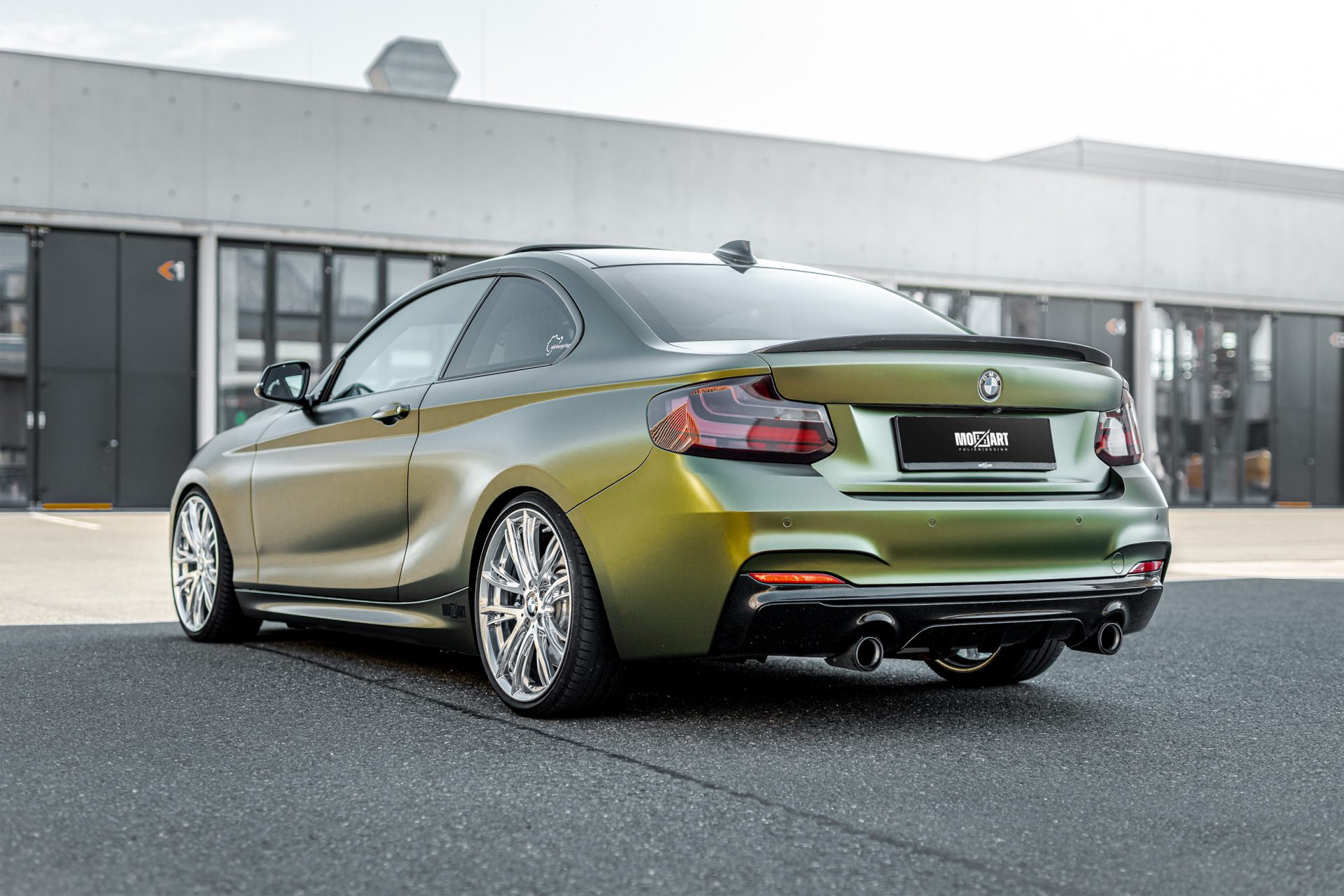 Eine Heckansicht von einem zweier BMW, voll foliert in einer gold-grün schimmernden speziellen flipflop Folie mit einem seidenmattem Finish. PDC wurden ausgebaut und foliert. Die Parksensoren sind somit ausgeschnitten.