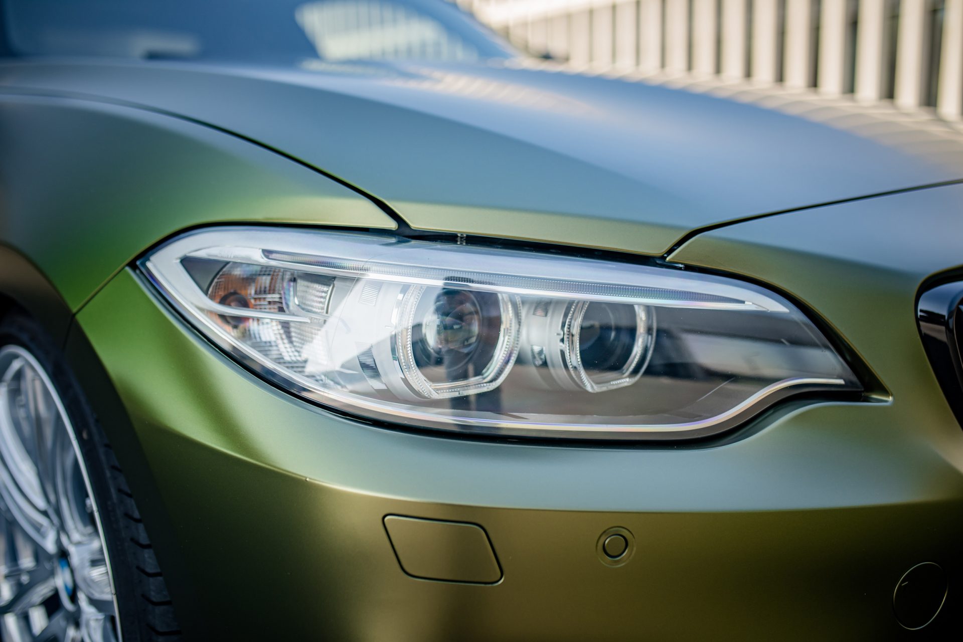 Detailbild von einem zweier BMW, voll foliert in einer gold-grün schimmernden speziellen flipflop Folie mit einem seidenmattem Finish. PDC wurden ausgebaut und foliert. Die Parksensoren sind somit ausgeschnitten.