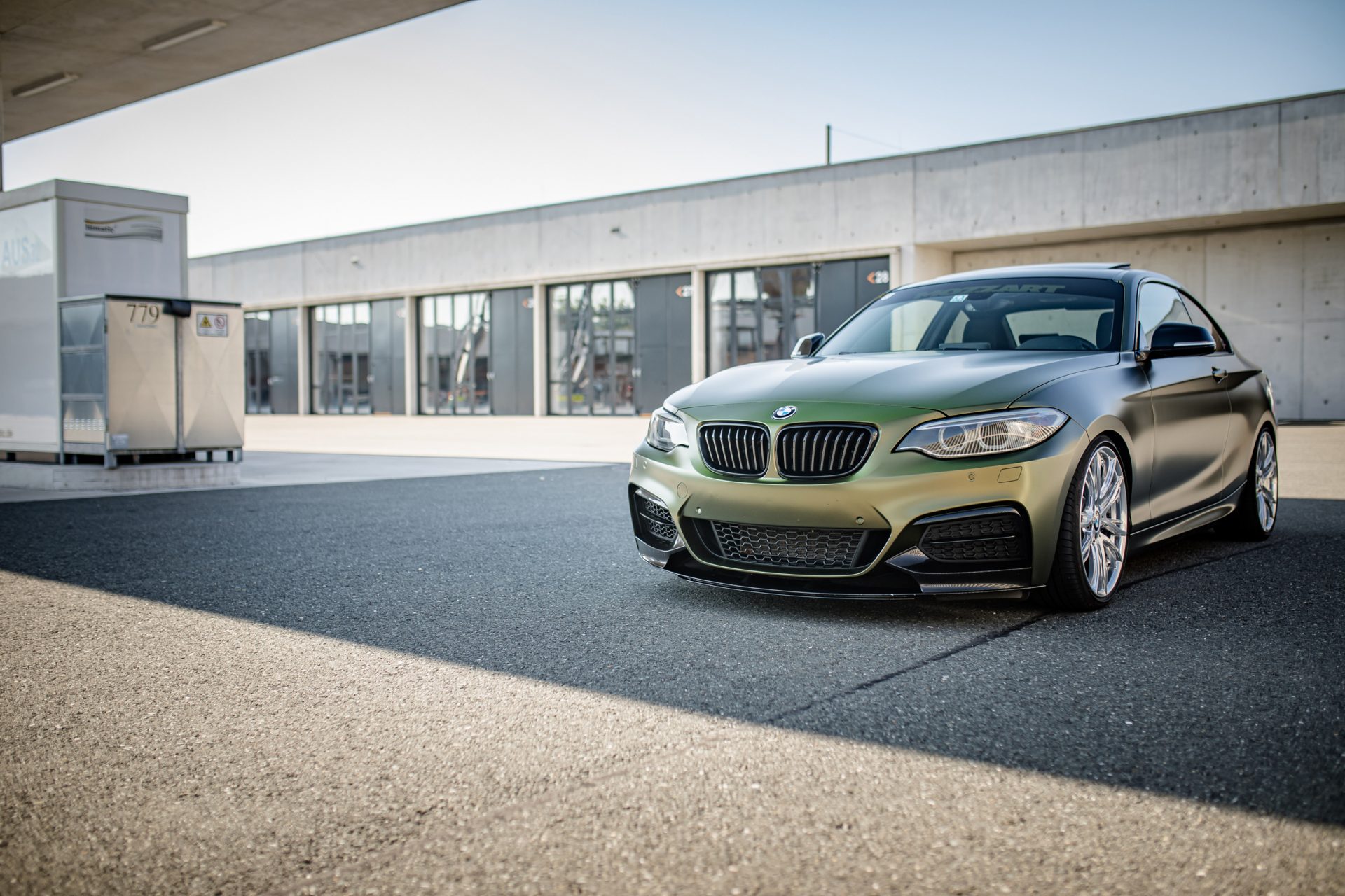 Eine Frontansicht von einem zweier BMW, voll foliert in einer gold-grün schimmernden speziellen flipflop Folie mit einem seidenmattem Finish. PDC wurden ausgebaut und foliert. Die Parksensoren sind somit ausgeschnitten.