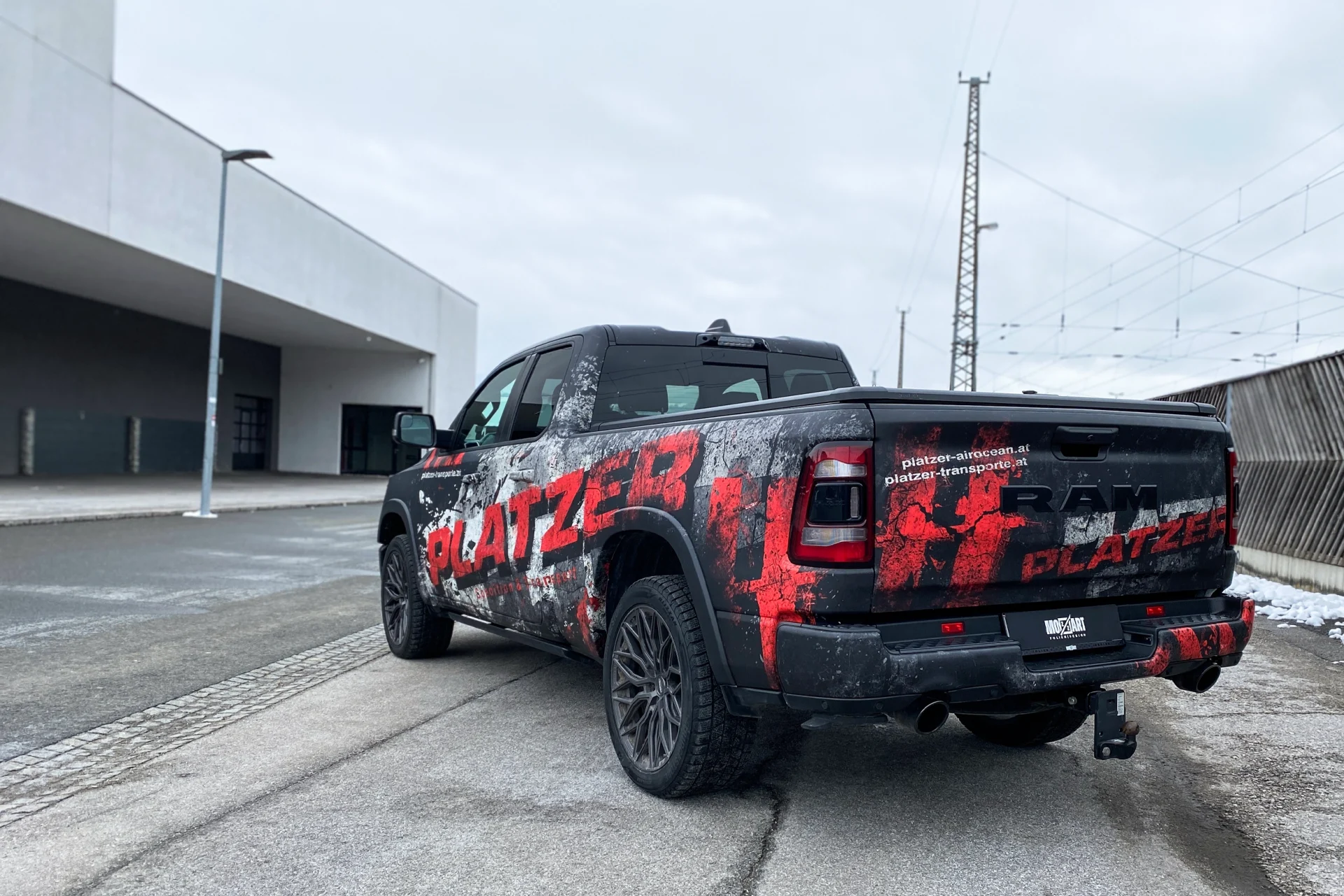 Heckansicht Dodge Ram mit used-look Digitaldruckfolierung mit matt schwarz und roter Platzer Transporte Beschriftung